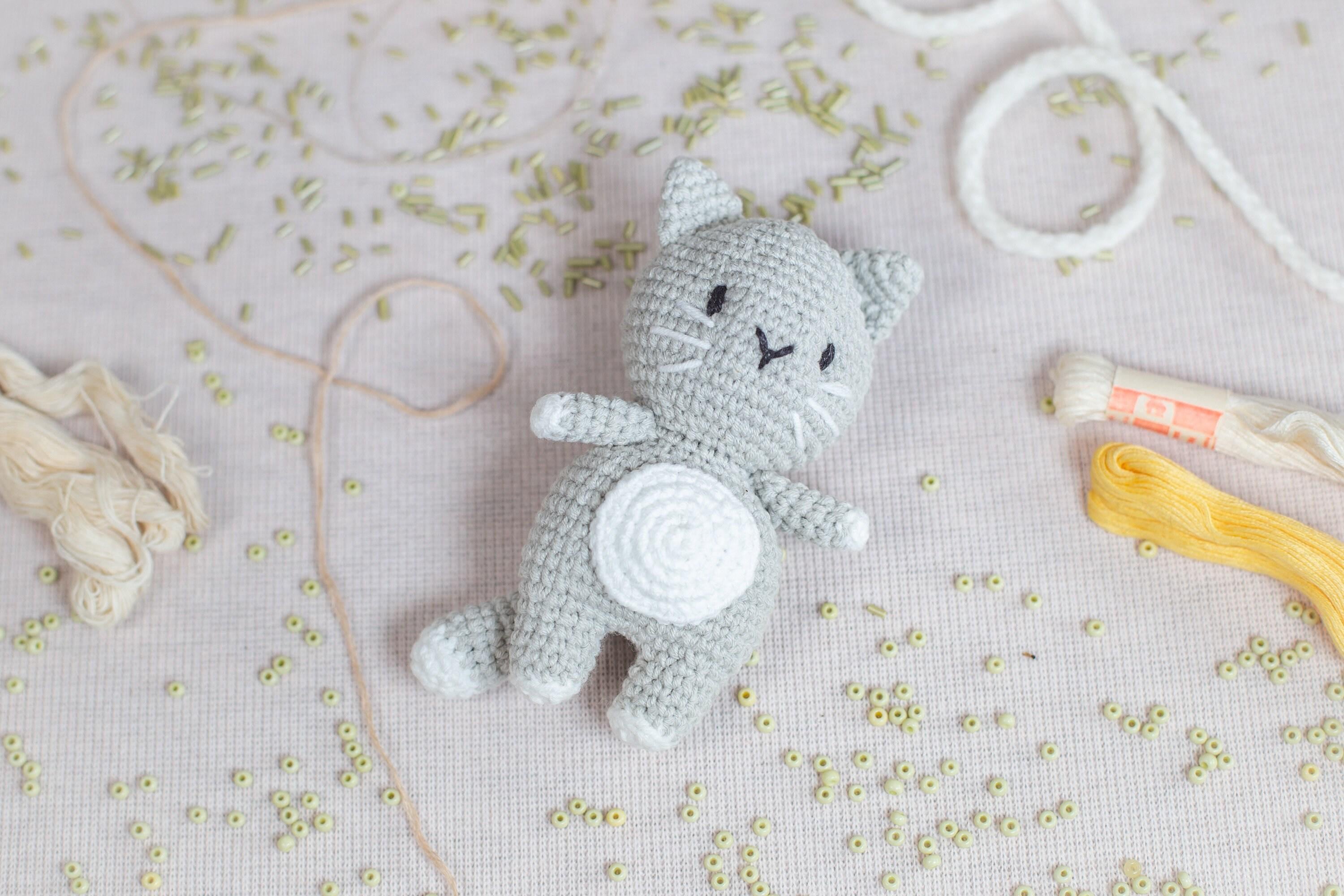 a crocheted cat sitting next to a pair of scissors